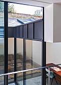 View through glass wall into living room with sofa and desk in extension