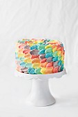A rainbow petal birthday cake on a cake stand