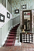 Winding staircase with red runner on white-painted wooden steps in rustic hallway