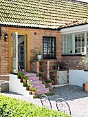 Brick house in sunlight with open front door and runner on front steps