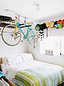 Rennrad auf Regal über Bett in Jungenzimmer mit Schildkappen-Sammlung