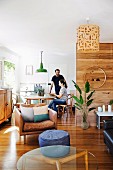 Couple in bright, open-plan interior with dining and lounge areas, parquet floor and modern wood-panelling