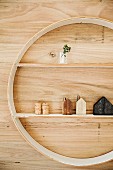 Rundes Wandregal mit weißen Fachböden, minimalistisch dekoriert mit Holzhäuschen an Holzverkleidung