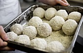 A chef holding a baking tray of arancini