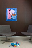 Blue artwork on dark brown wall and elegant lounge chairs