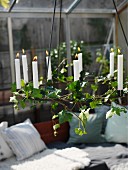 White lit candles in chandelier wound with ivy