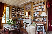 Nostalgisches Wohnzimmer mit Bücherwänden, antiken Möbeln und schweren Vorhängen