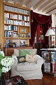 Bookcase, antique furniture, curtain on doorway and scatter cushions on armchair in classic living room