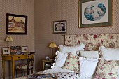 Traditionelles Schlafzimmer mit klassischer Tapete, Textilien mit Rosenmuster und antiken Möbeln