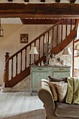 Turned staircase balustrade in open-plan, elegant, renovated interior with antique cabinet