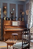 Klavier vor graublauer Holzverkleidung in elegantem Salon