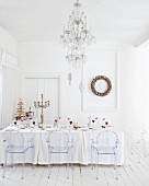 Weiß gedeckter Tisch mit Weihnachtsdekoration in schneeweissem Raum