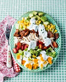 A mixed vegetable salad with chicken, bacon, eggs and a yoghurt dressing