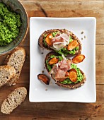Crostini topped with pea cream, roasted carrot slices and ham