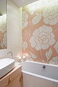 Florales Fliesenmosaik hinter Badewanne und Quasten an den Schubladen eines Wachtischs