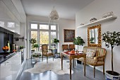 Eclectic, open-plan interior with modern kitchen counter, dining area with antique furniture and partition wall screening living area