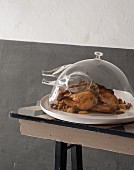 Roast chicken with mushrooms under a glass chicken-shaped cloche