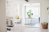 White-painted armchairs in front of wide, open doorway leading to dining room