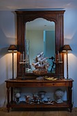 Table lamps on antique console table and wood-framed mirror