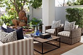 Outdoor seating area with coffee table, wicker armchairs, sofa and decorative terracotta pots in background