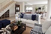 White, open-plan interior with wooden installations, blue and white geometric scatter cushions and deep blue ottomans