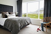 Doppelbett im Schlafzimmer mit Landschaftsblick durch Panoramafenster