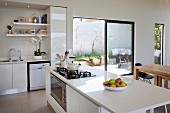 White open-plan kitchen with island counter and open terrace doors