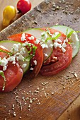 Sliced tomatoes and cucumbers with feta cheese and mint on a wooden board