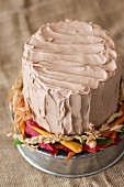An autumnal chocolate pumpkin layer cake on a rustic cake stand with autumn leaves