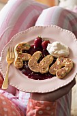 Letter-shaped pancake on berry purée with cream