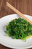 Wakame salad with sesame seeds on a wooden mat