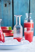 Watermelon lemonade in bottles and a glass