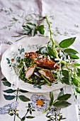Chicken with an aromatic breadcrumb crust on a bed of spring vegetables with pea flowers