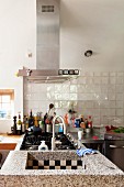 Küchenzeile mit Edelstahl-Elementen und Gasherd, zweiseitig zugängliche Steinspüle mit Schachbrettfliesen