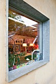 View of art collection and bicycle in interior seen through window with galvanised steel frame