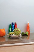 Vegetables and stacked white plates on grey, stone worksurface