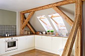 Kitchen in attic room with sloping ceiling and exposed wooden roof structure