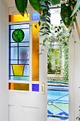 Geöffnete Schiebetür mit farbiger Glasfüllung, Blick auf Indoor-Pool