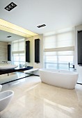 Cool, white designer bathroom with dark accents formed by wall-mounted radiators and washstand counter mounted on continuous mirrored wall