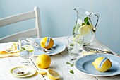 Gedeckter Tisch mit Zitronen und Zitronenwasser