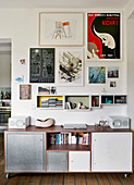 Sideboard with galvanised and white metal doors below shelving units and posters on wall