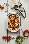 Shell pasta with a ricotta filling and puttanesca sauce, basil pesto, Parmesan cheese, a cheese grater and cherry tomatoes