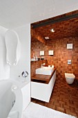 Blick von Badewanne in Nische, durch raumhohem Durchgang in holzverkleidetes Bad, Mosaik Holzplatten, mit Waschtisch und Hänge-WC