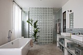 Bad mit freistehender Badewanne, Waschtischzeile mit zwei Aufbaubecken, im Hintergrund Glasbausteinwand vor Duschbereich