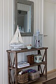 Model boat and lantern on old wooden shelves below framed mirror on white wooden wall