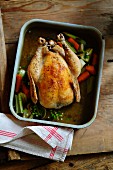 Roast chicken with carrots and leek in a roasting tin