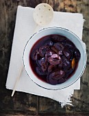 A bowl of stewed damsons with a wooden spoon