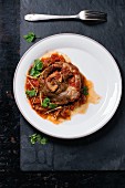 Braised veal knuckle with tomatoes and parsley (seen from above)