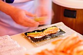 Sushi with salmon and nori being made