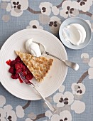 A slice of almond tart with raspberry compote and cream